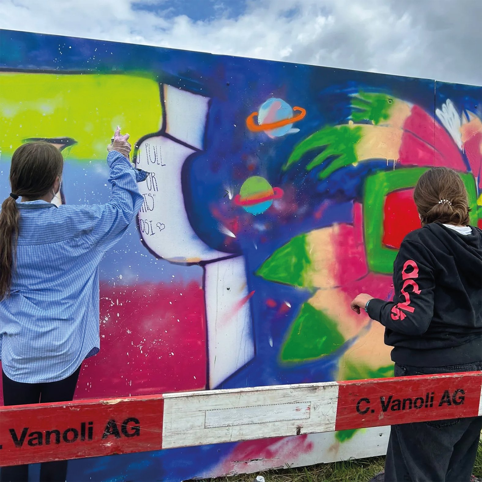 Schulkinder aus Meggen beim Besprayen der Baustellenwand am Lerchenplatz.